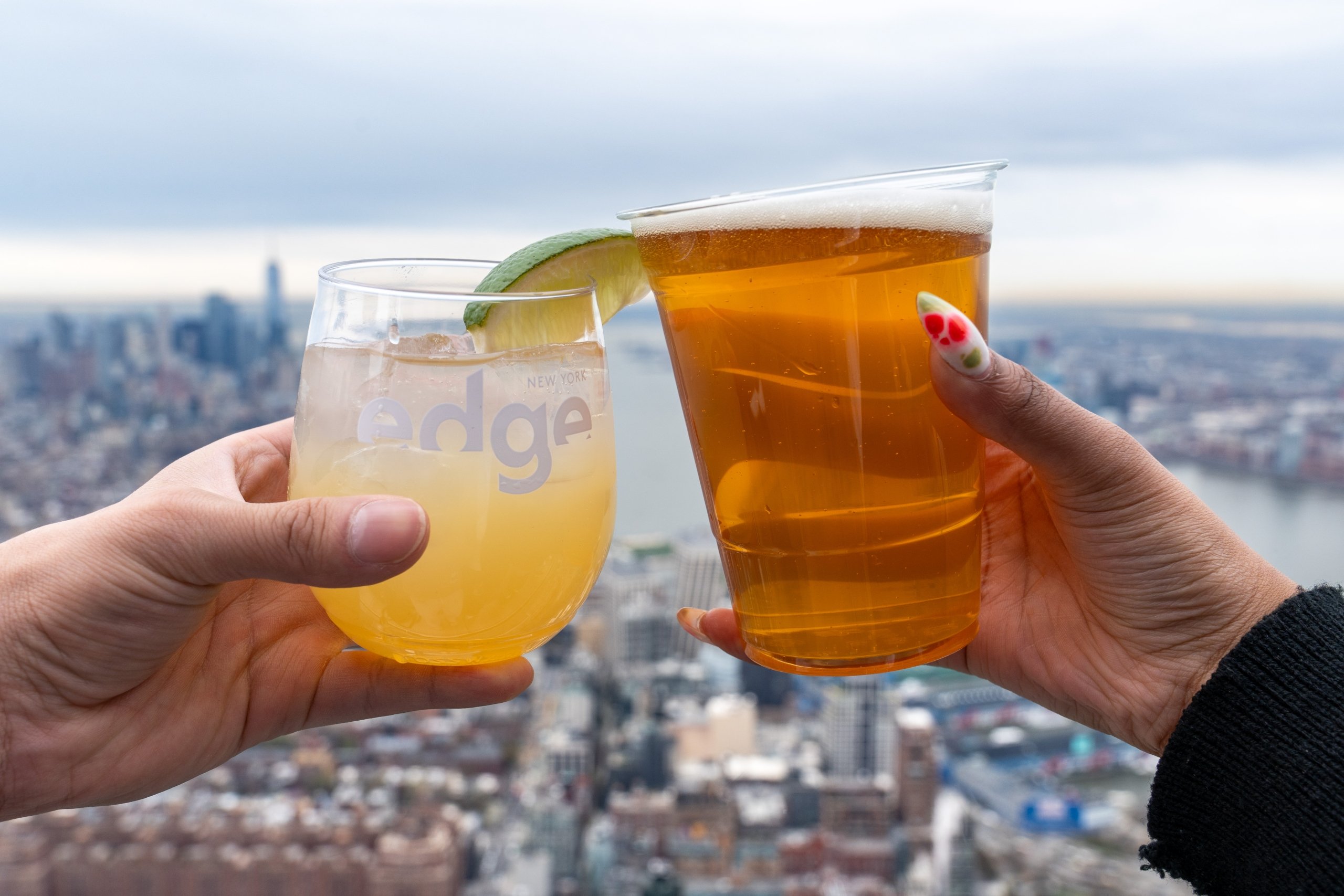 Two people clink glasses overlooking New York city on a sunny day