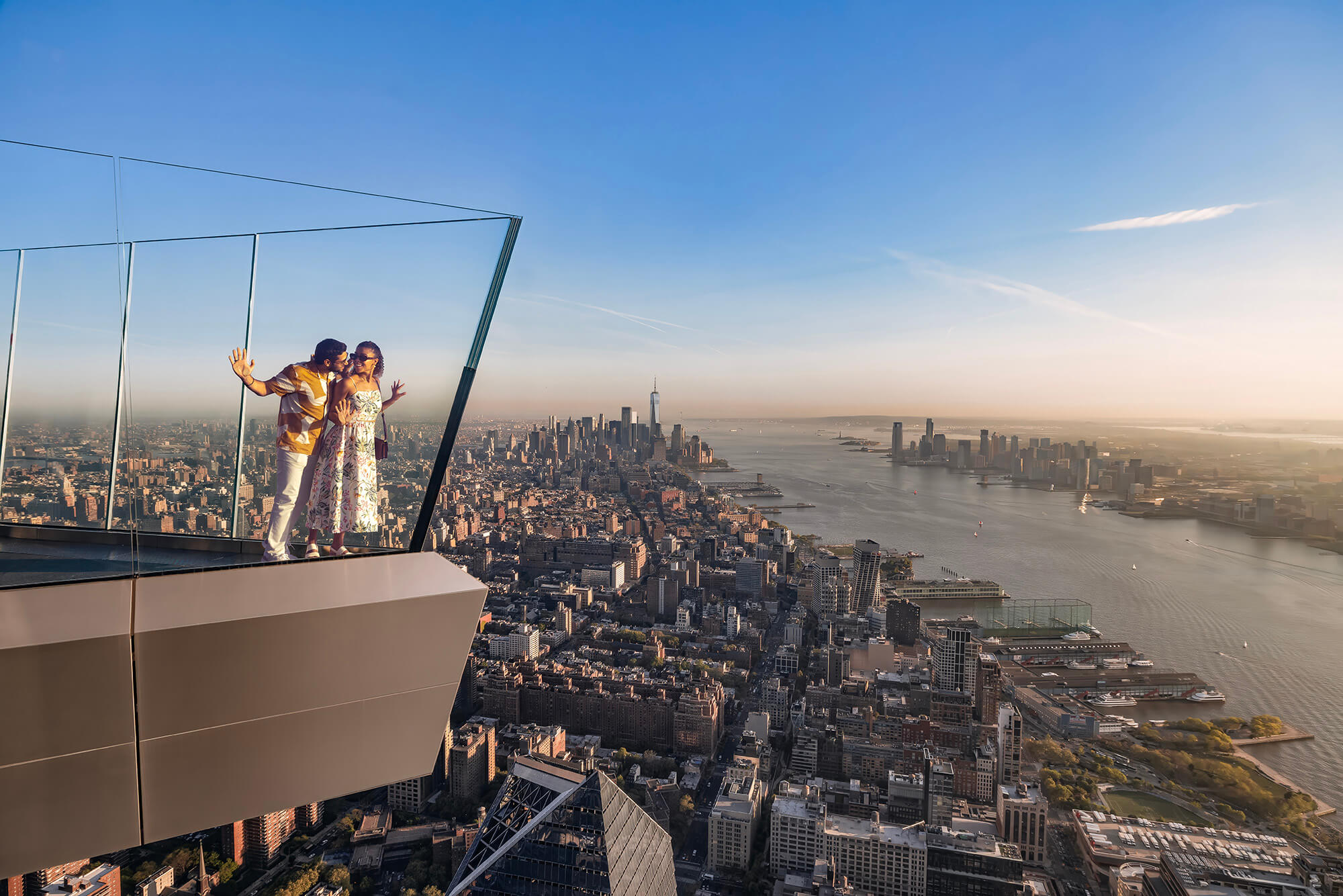 A couple embrace while looking out over New York City at sunset from The Edge