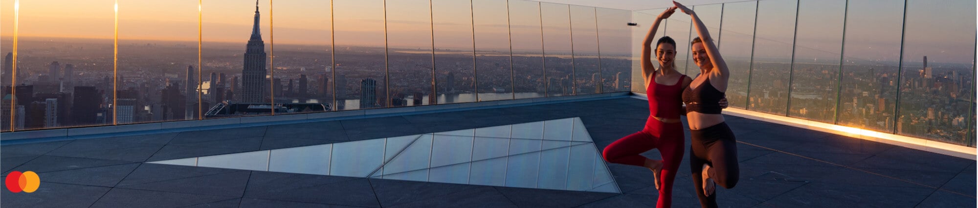 Two women in a yoga pose at The Edge at sunset
