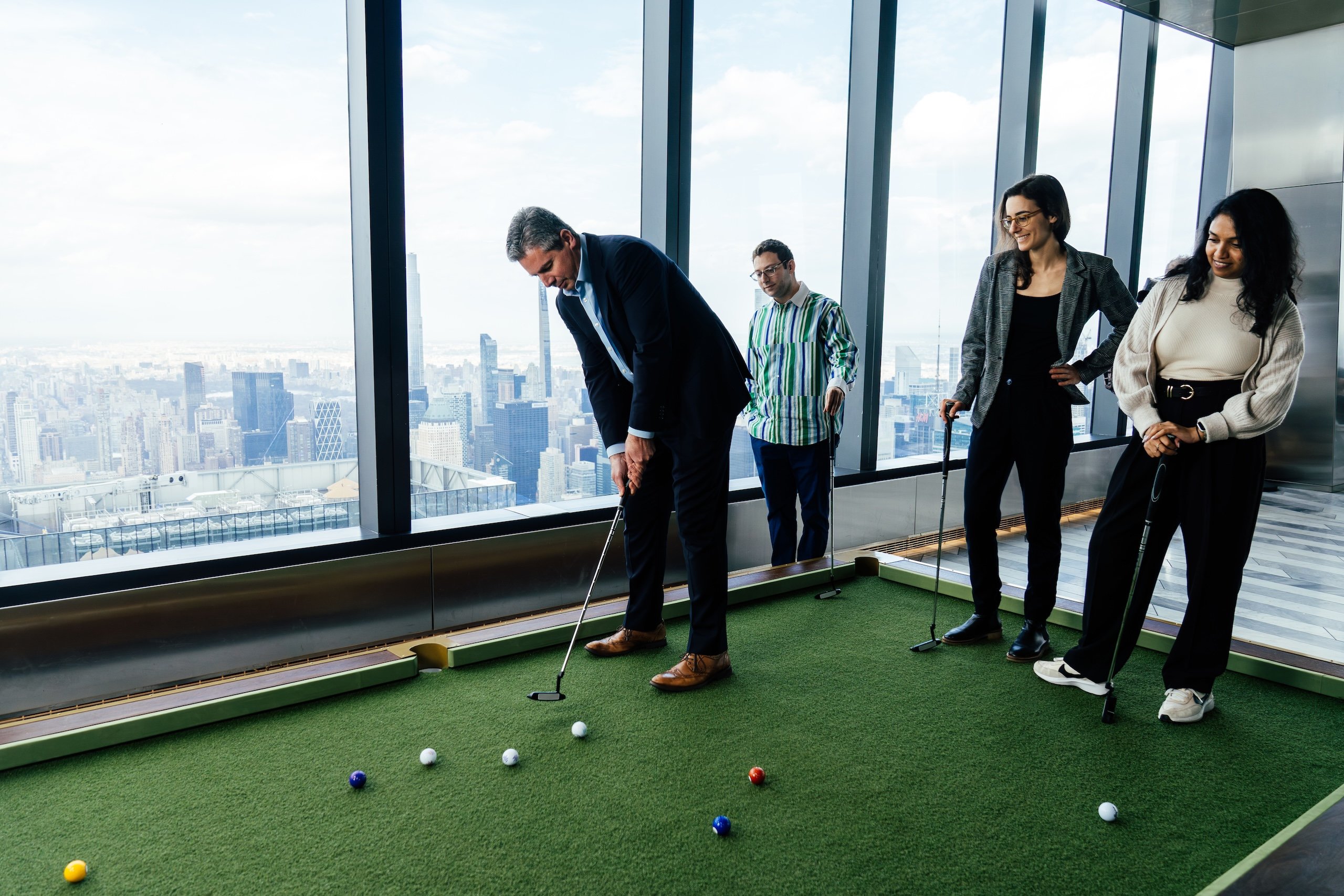 A group of corporate colleagues play golf together at The Edge, the New York skyline in the background