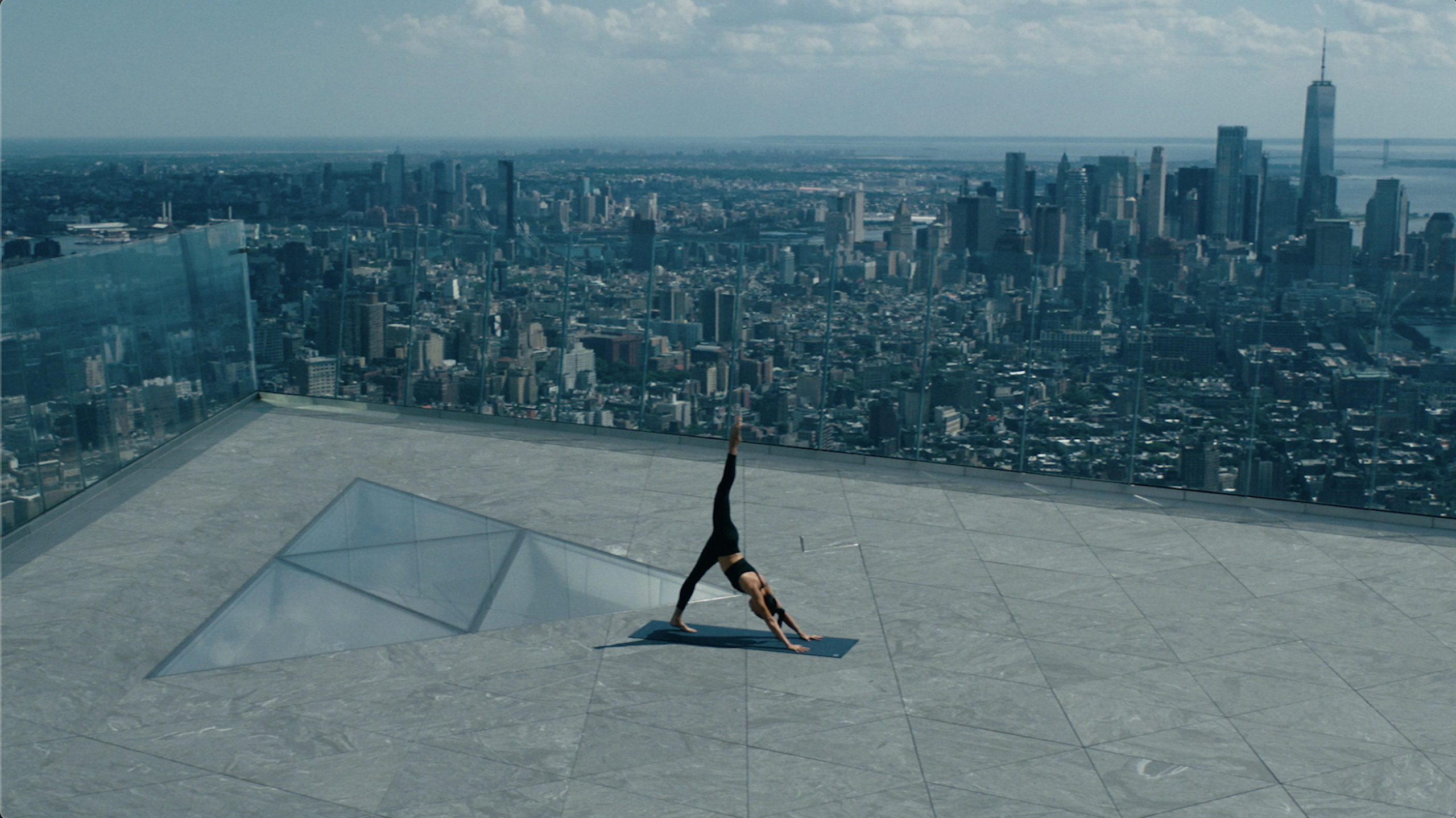 A woman does a yoga pose at The Edge overlooking New York city
