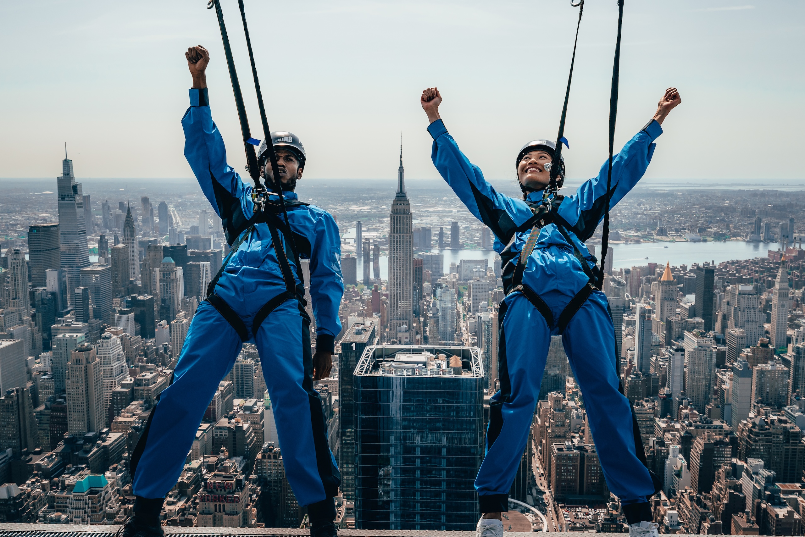 Two people pump fists in the air as they lean back during City Climb at The Edge