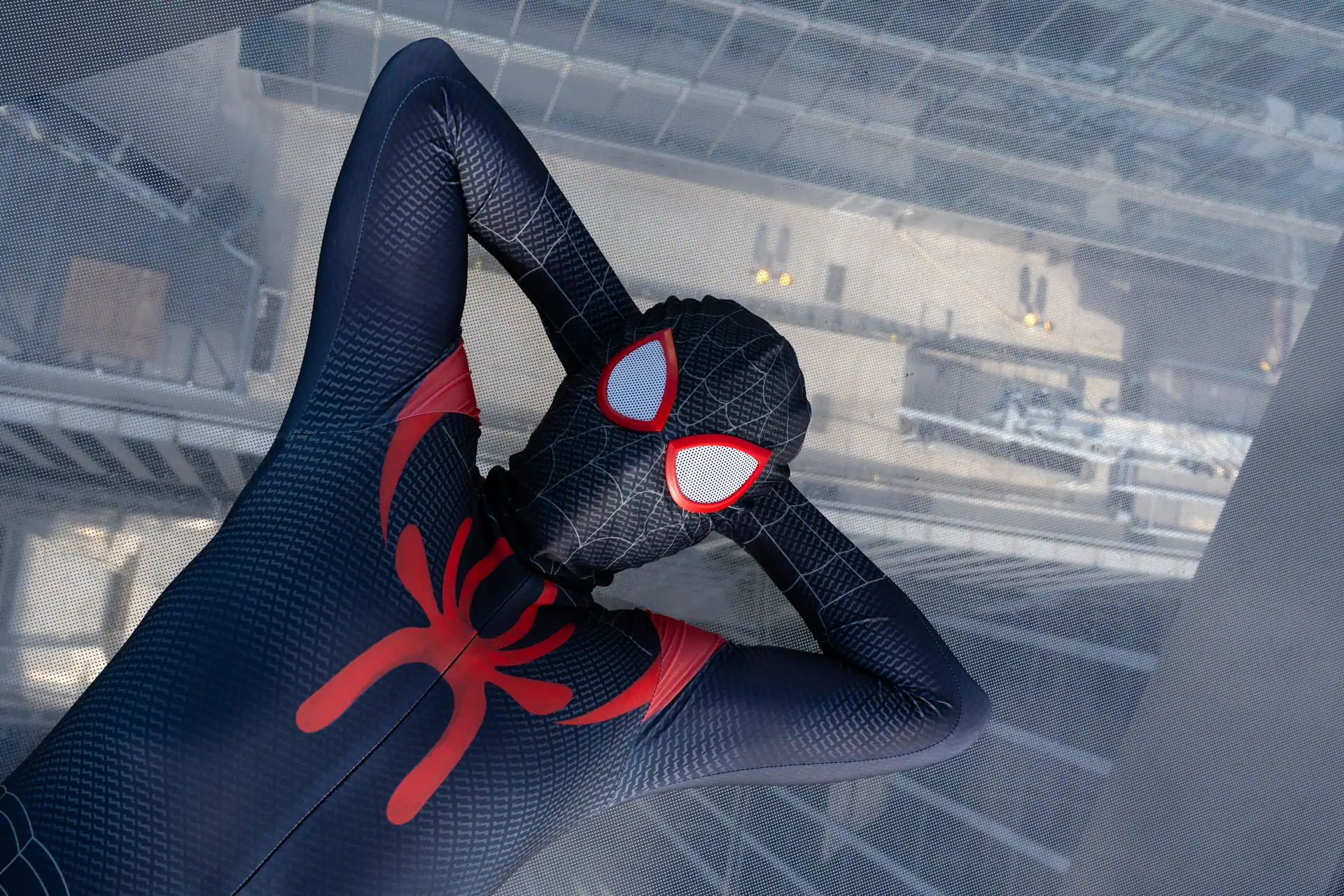 Spider-Man with hands behind his head laying on the glass at The Edge NYC