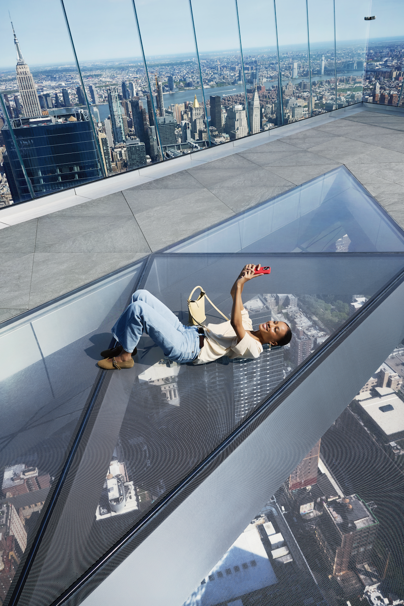 woman posing for a selfie laying on the glass at The Edge NYC