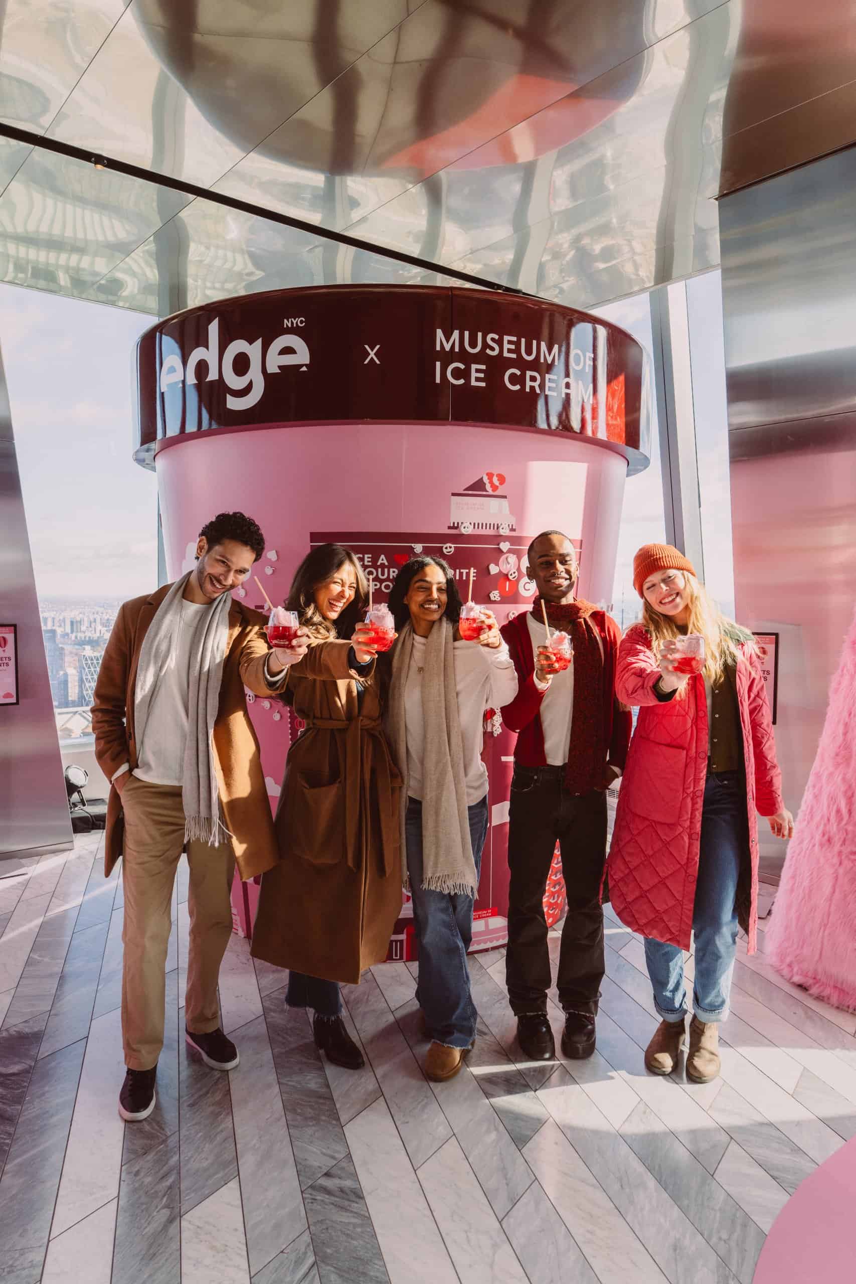 friends holding up cocktails at the edge nyc